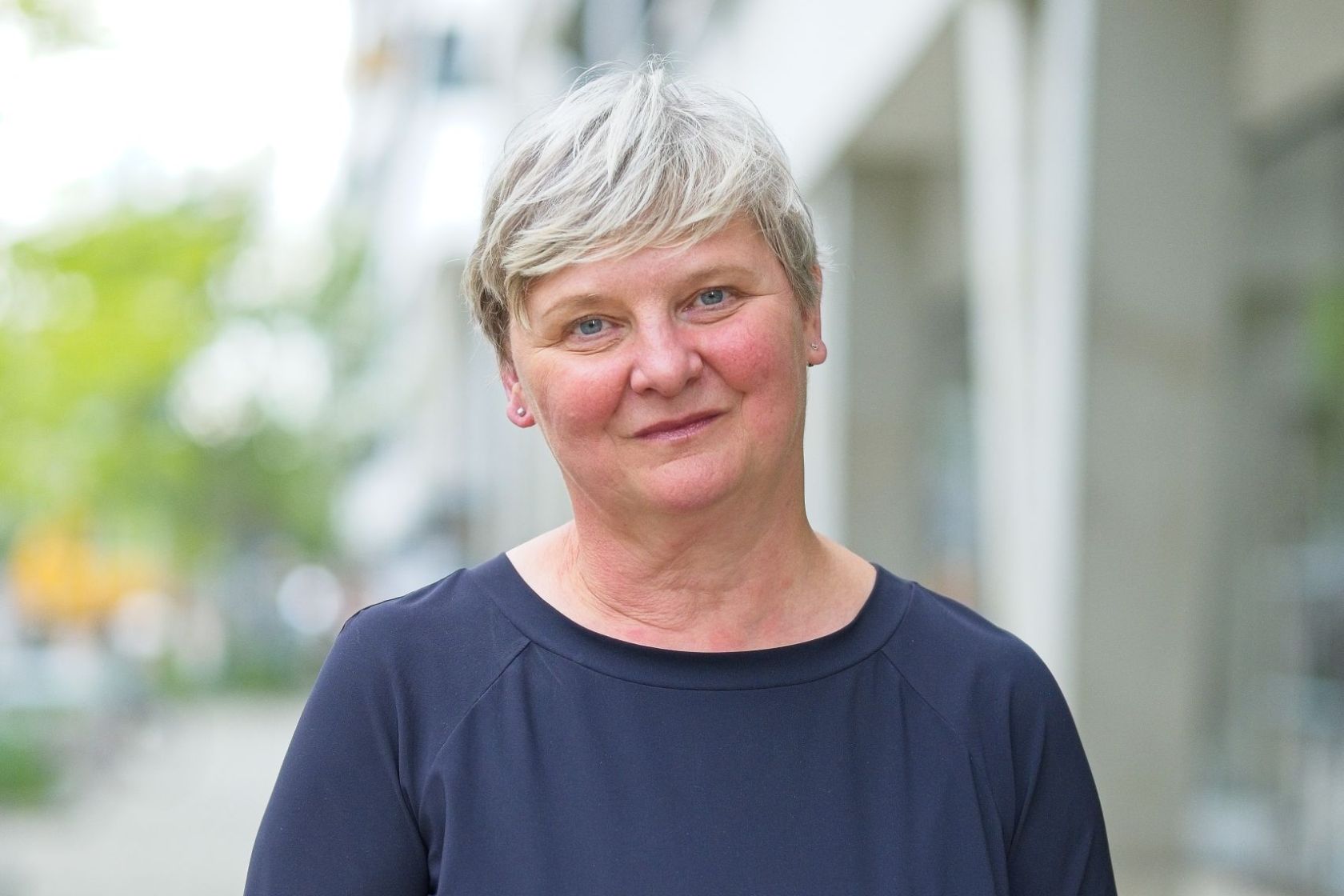 Sandra Frauenberger lächelt in die Kamera. Im Hintergrund ist eine Straße zu sehen.