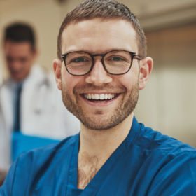 Mann mit Hornbrille freut sich mit Hilfe des waff einen Job als Pflegeassistenz gefunden zu haben.