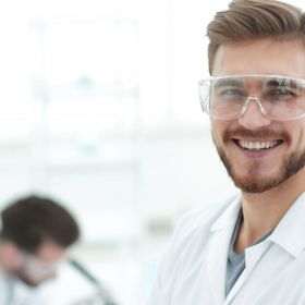 Laborassistent im Arbeitsumfeld lächelt ins Bild.