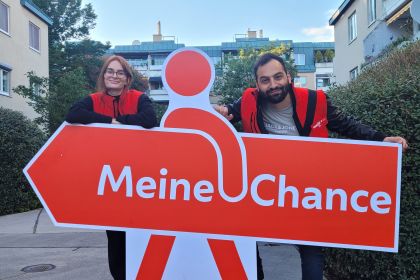 Zwei Promotor*innen im Gemeindebau mit dem "Meine Chance" Schild