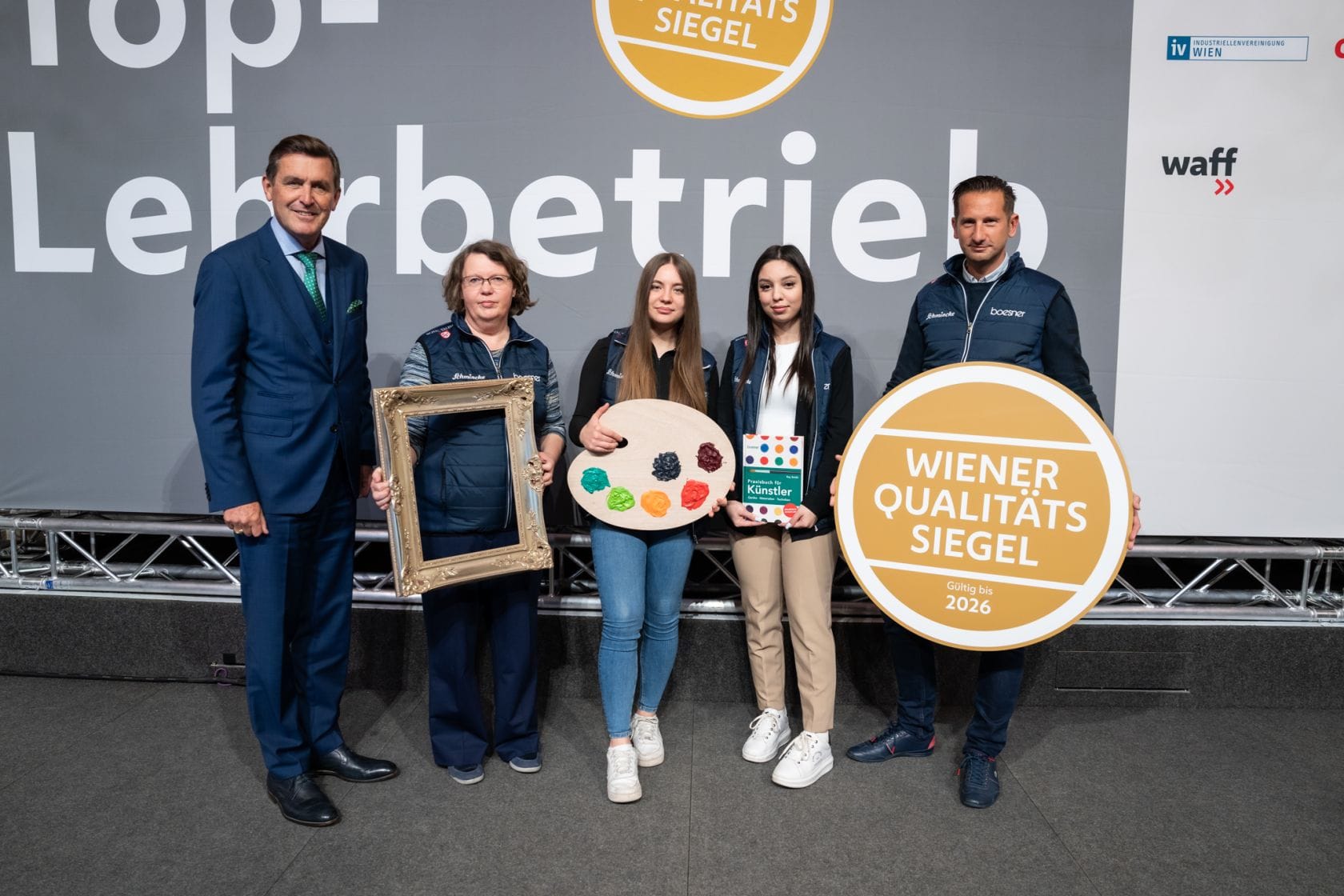 Stadtrat Peter Hanke mit Personen eines ausgezeichneten Lehrbetriebs auf der Bühne im Rathaus