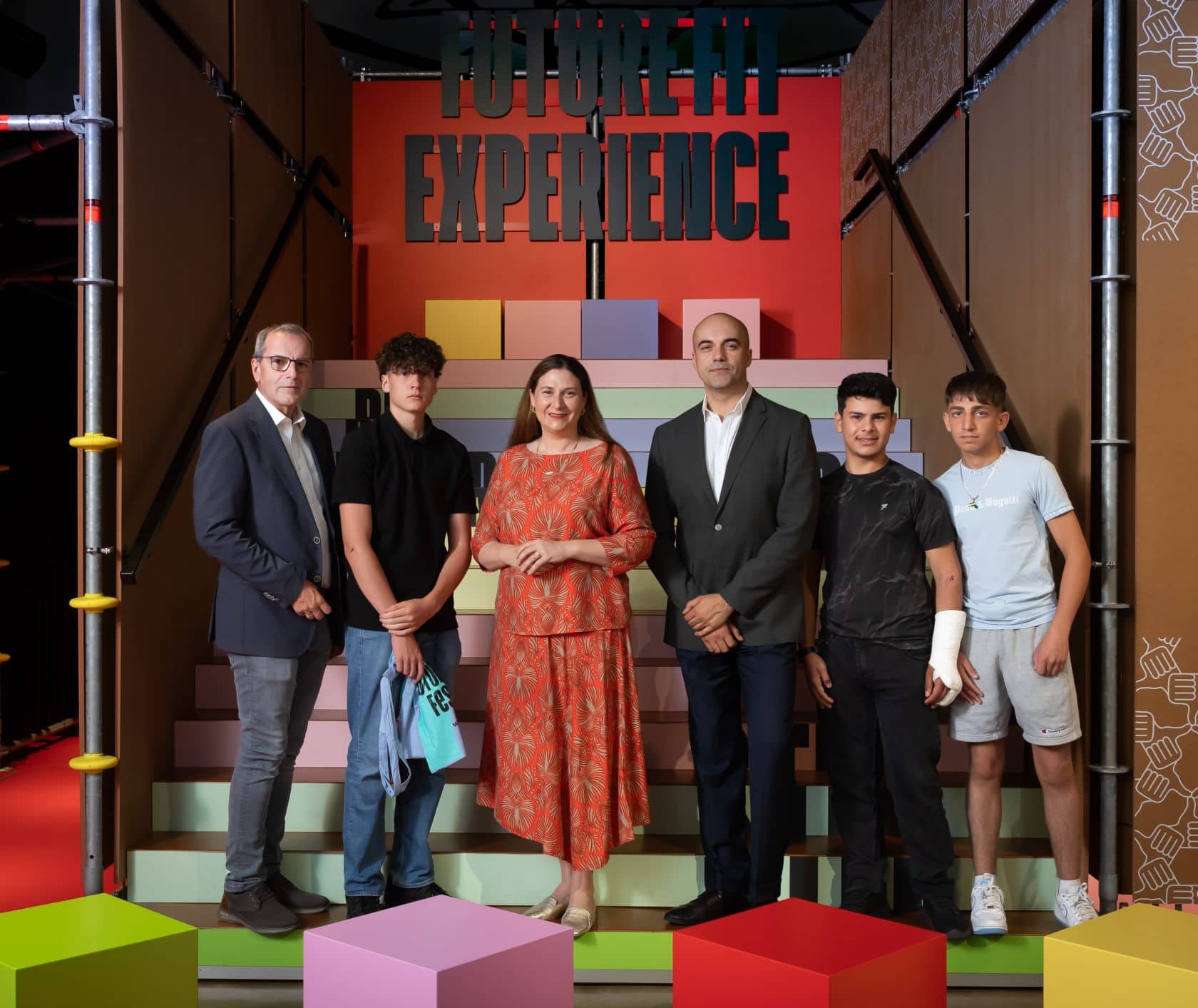 Christian Meidlinger, Barbara Novak, Marko Miloradovic und drei junge Burschen stehen vor bunten Stufen in der Future Fit Experience