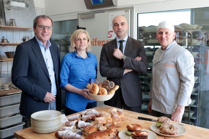 Christian Meidlinger, Alexandra und Stefan Szihn und Marko Miloradovic stehen hinter einem Tisch mit Backwaren in einer Bäckereie
