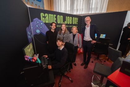 Arbeitsministerin Korinna Schumann, Vizebürgermeisterin und Arbeits- und Wirtschaftsstadträtin Barbara Novak sowie Roman Fuchs, stv. Generaldirektor der Wiener Stadtwerke, überzeugen sich von den Gaming Skills von Gregor Peruccio (sitzend), der sich über die Gaming Challenge ein kaufmännisches Praktikum bei Wien Energie erspielt hat. Sebastian Genn Schüssler (stehend) hat ebenfalls mitgespielt und sich so ein Praktikum bei den Wiener Netzen gesichert.