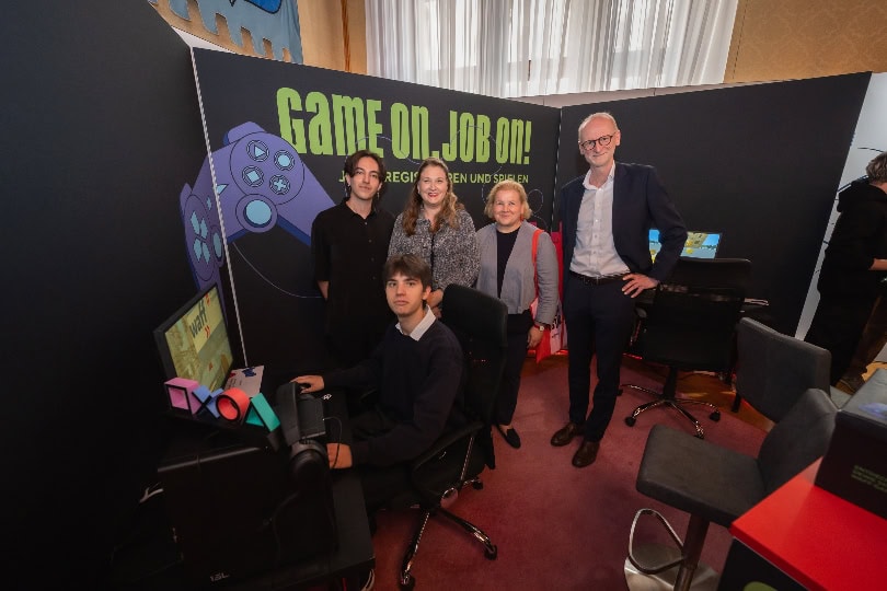 Arbeitsministerin Korinna Schumann, Vizebürgermeisterin und Arbeits- und Wirtschaftsstadträtin Barbara Novak sowie Roman Fuchs, stv. Generaldirektor der Wiener Stadtwerke, überzeugen sich von den Gaming Skills von Gregor Peruccio (sitzend), der sich über die Gaming Challenge ein kaufmännisches Praktikum bei Wien Energie erspielt hat. Sebastian Genn Schüssler (stehend) hat ebenfalls mitgespielt und sich so ein Praktikum bei den Wiener Netzen gesichert.